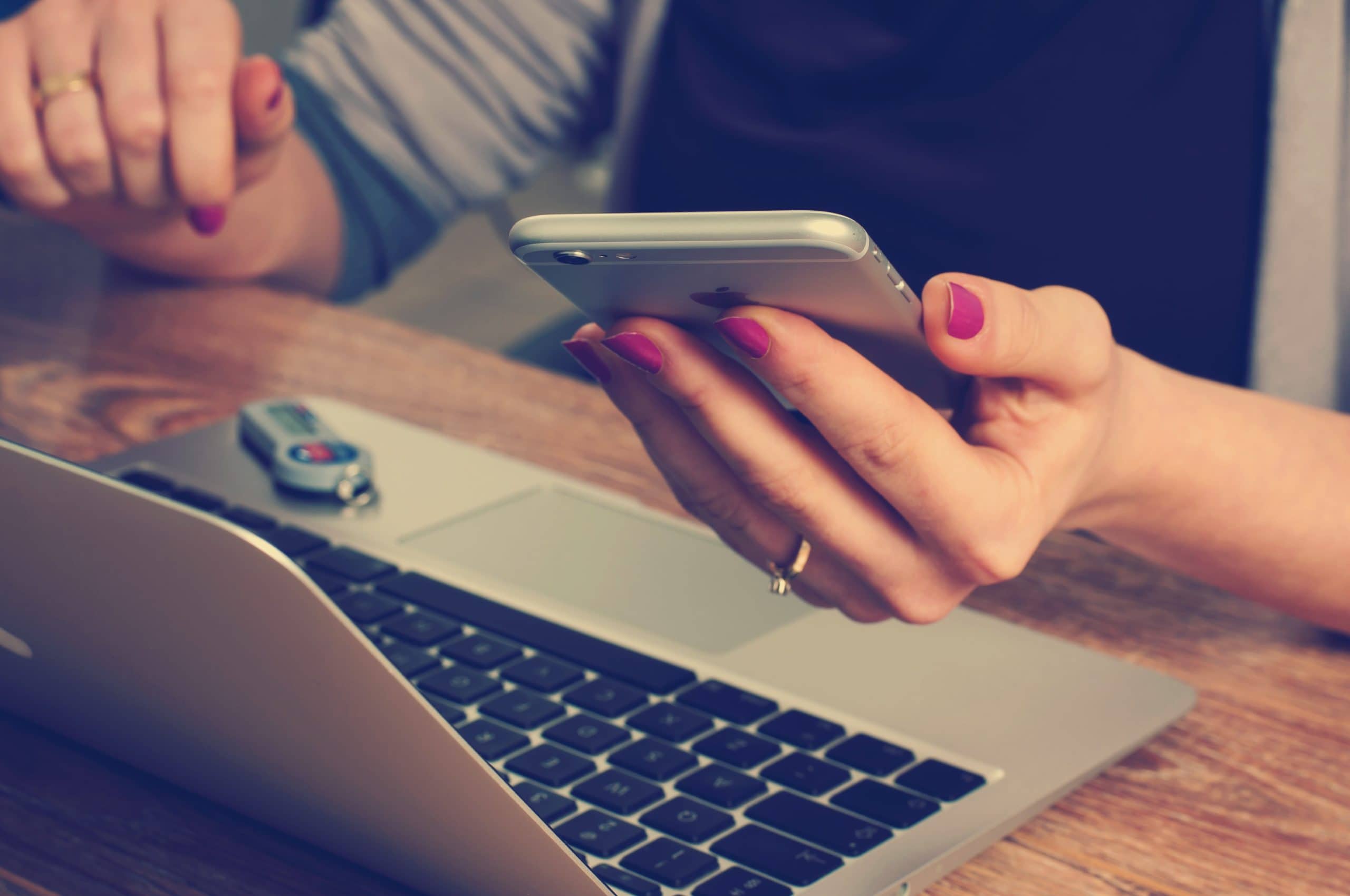 woman comparing info on phone and laptop